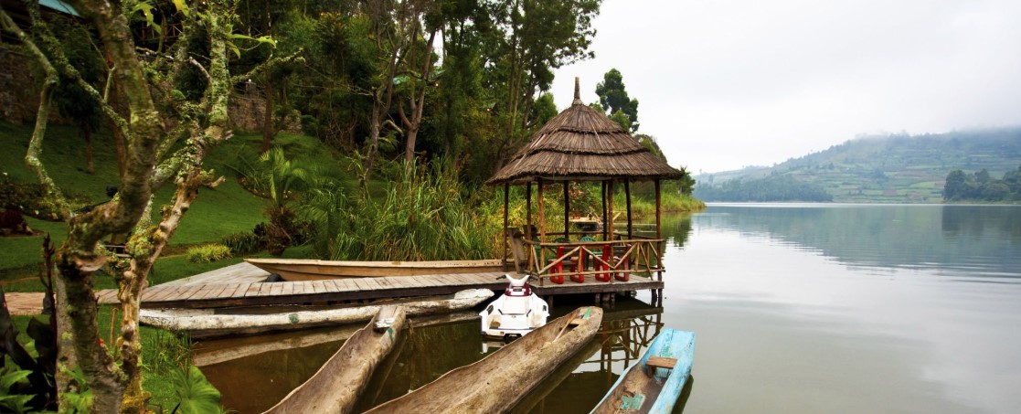 Colorful traditional boats anchored near the shore of Lake Bunyonyi, with vibrant reflections in the water.
