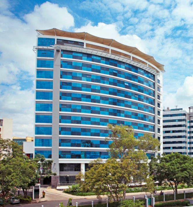 A scenic view of Kigali City with modern buildings, clean streets, and green hills under a clear blue sky.